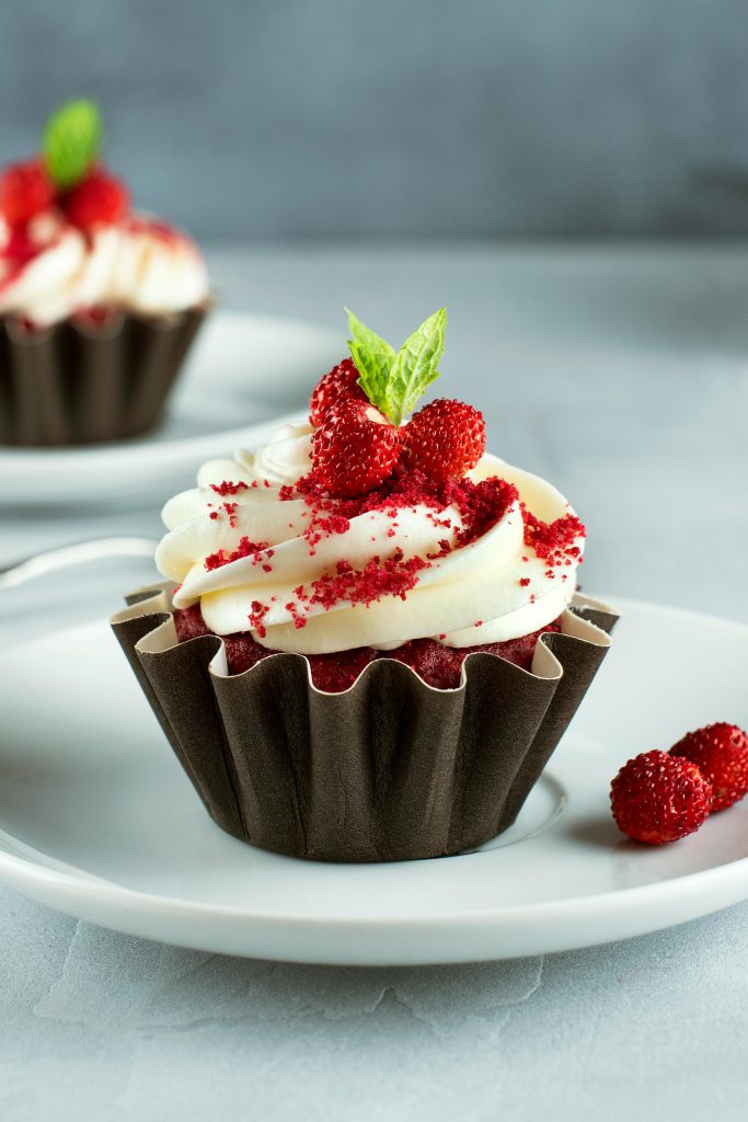 Indulgent red velvet cupcake adorned with fresh berries and cream cheese frosting.