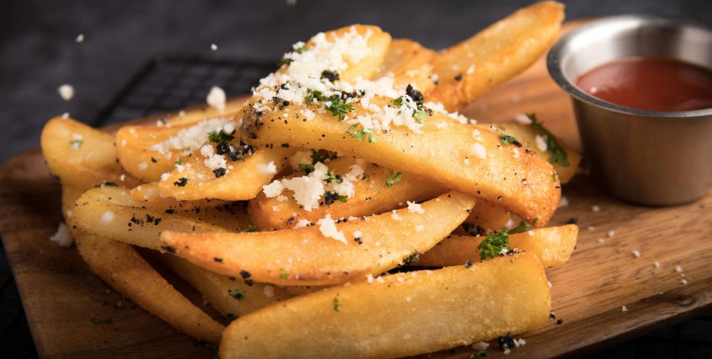 Delicious golden french fries topped with grated cheese and herbs, served with ketchup.