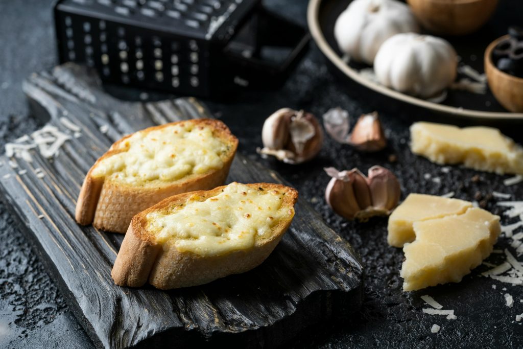 Close-up of warm cheese bread with garlic on a rustic board, perfect for cozy food photography.