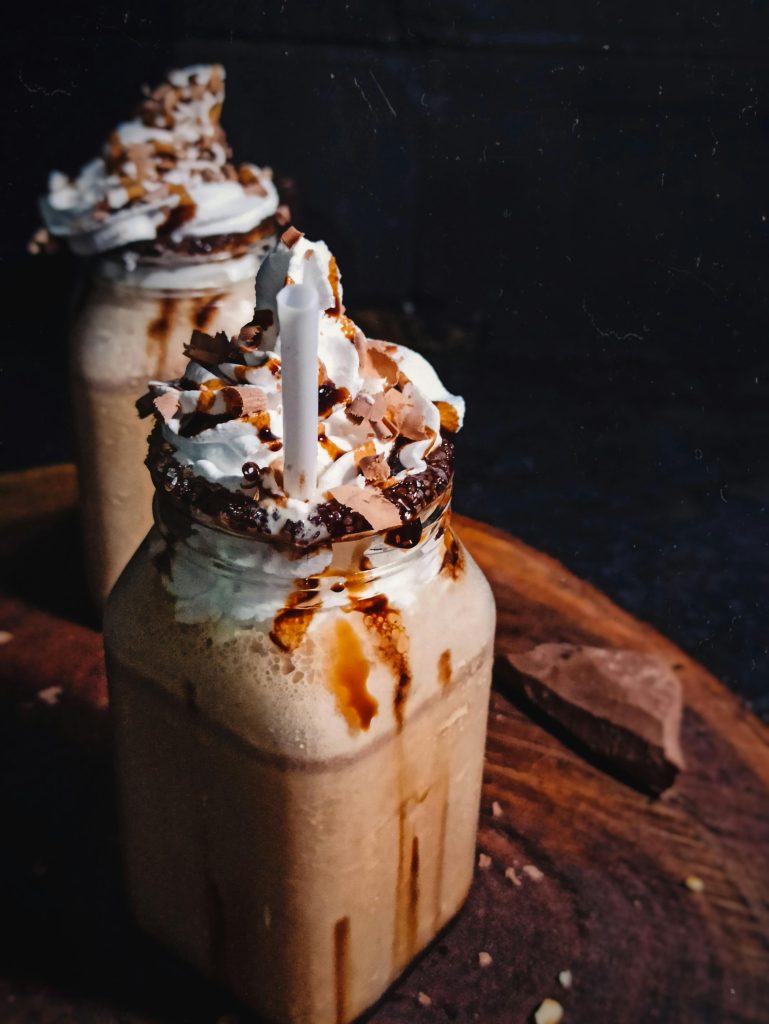 Delicious iced coffee topped with whipped cream and chocolate in a rustic setting.